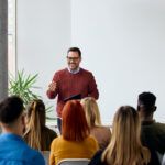 Corporate speaker delivering a motivating training session to a group of diverse employees.