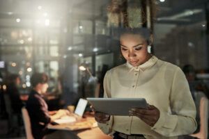 Shot of an attractive young designer working late at the office with her colleagues in the background