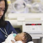 Neonatal nurse holds newborn baby in hospital