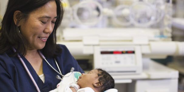 Neonatal nurse holds newborn baby in hospital