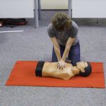 First aider performs CPR on doll