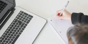 a photo of a woman taking notes in front of a computer
