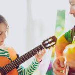 Music therapist plays guitar with young girl during music therapy session