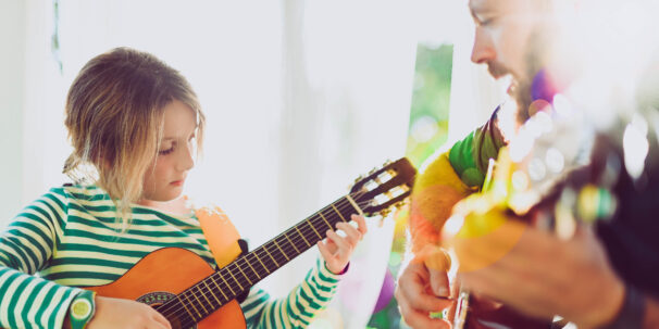 Music therapist plays guitar with young girl during music therapy session