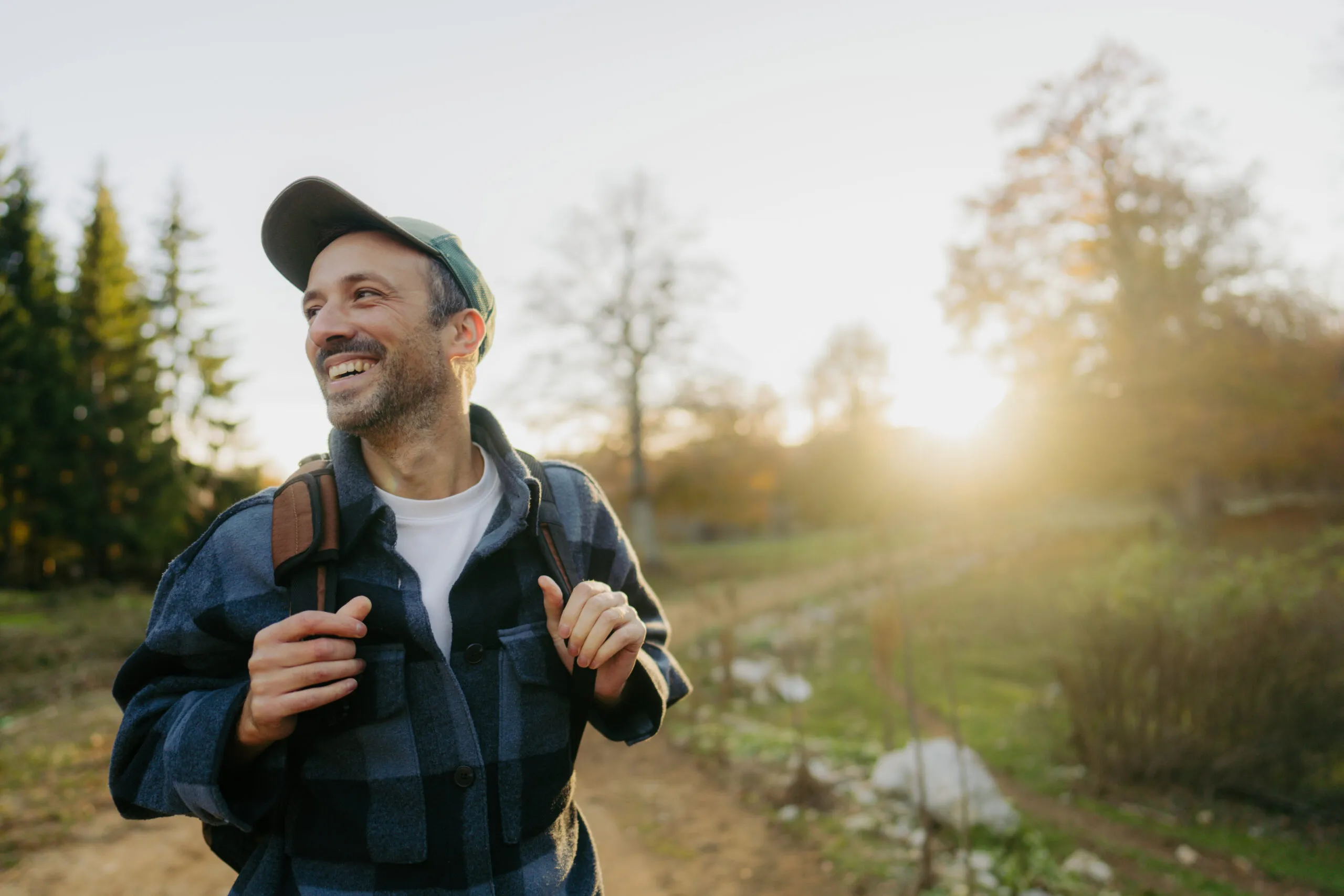 Individual out in nature, smiling as the sun rises.