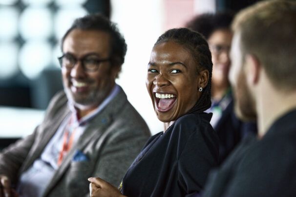 Three people laughing together in an audience.