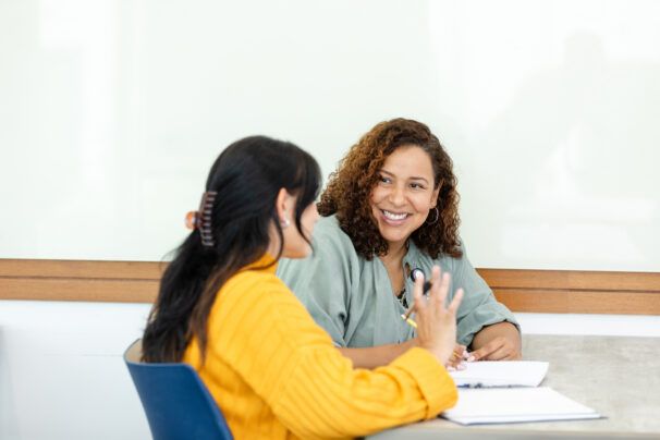 An attentive professor listens as a student discusses an assignment during a tutoring session.